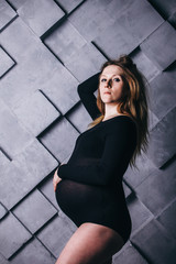 A pregnant woman in lingerie with a big belly in the ninth month of pregnancy is posing next to a...