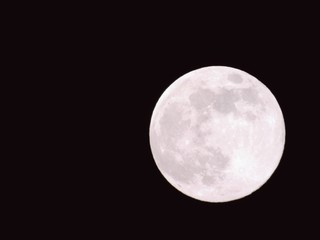 An amazing photography of the full moon over the city of Genova by night with a great clear and blue sky in the background and some stars.