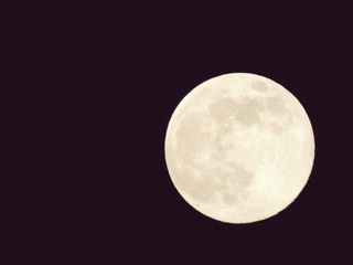 An amazing photography of the full moon over the city of Genova by night with a great clear and blue sky in the background and some stars.