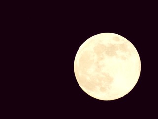 An amazing photography of the full moon over the city of Genova by night with a great clear and blue sky in the background and some stars.