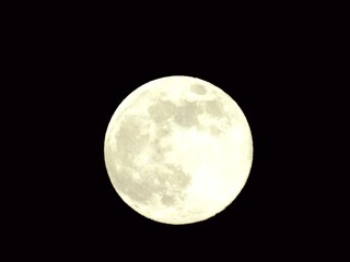 An amazing photography of the full moon over the city of Genova by night with a great clear and blue sky in the background and some stars.