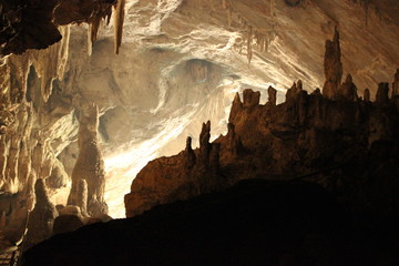 dark interoir of a large cave in Mae Hong Son state, Northern Thailand, viewing the opening from inside, seeing the stalactites and stalagmites  - obrazy, fototapety, plakaty