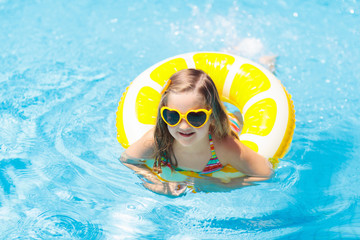 Child in swimming pool on ring toy. Kids swim.