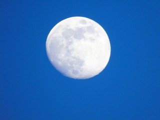 An amazing photography of the full moon over the city of Genova by night with a great clear and blue sky in the background and some stars.