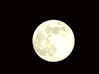 An amazing photography of the full moon over the city of Genova by night with a great clear and blue sky in the background and some stars.