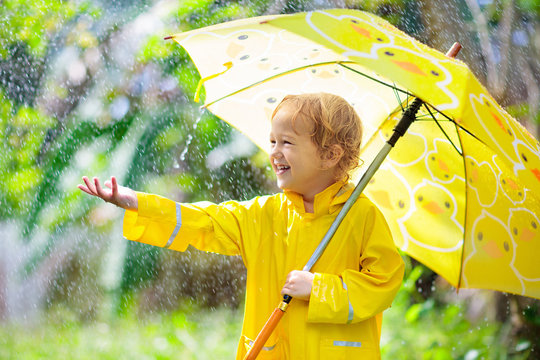 Child playing in the rain. Kid with umbrella.
