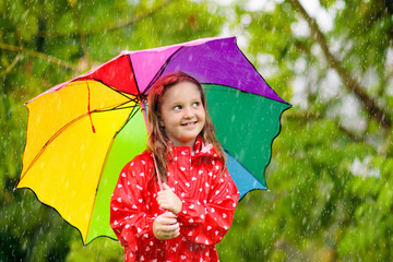 Kid with umbrella playing in summer rain.
