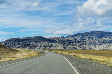 Beautiful view of Pavement road through sandstone mountain with dry yellow golden grass with cloud sky on the way from El Calafate to El Chalten in south Patagonia, Argentina