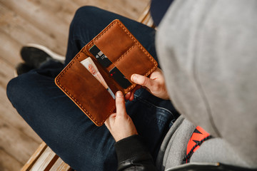 A man holding open a leather wallet with money