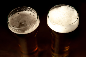 two beer glasses of fresh, tasty beer on a dark background