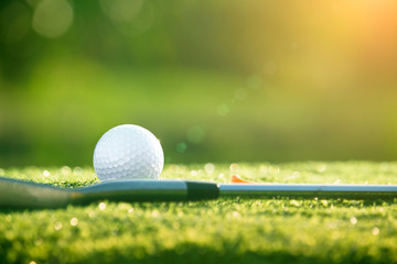 Golf clubs and golf balls on a green lawn in a beautiful golf course