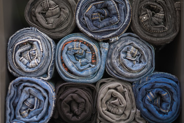 Fototapeta na wymiar Roll denim jeans arranged in the box, Jeans background