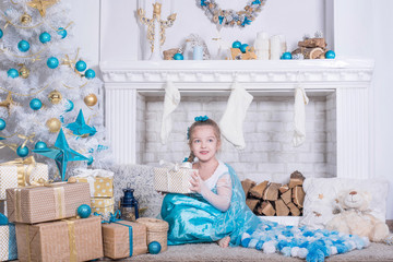 Children at Christmas tree and fireplace on Xmas eve. Family with kids celebrating Christmas at home. girl in blue dress decorating xmas tree and opening presents. Holiday gifts for kid 