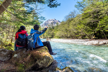 Man and woman sit on rock near Azusa river at Kamikochi in Northern Japan Alps.