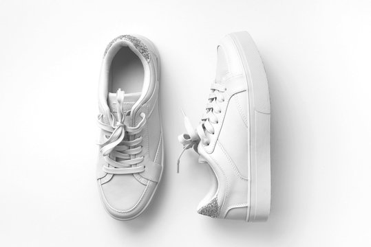White leather sneakers on white background. Pair of fashion trendy white sport shoes or sneakers with copy space for text or design. Overhead shot of new white sneakers,monochrome.Top view or flat lay