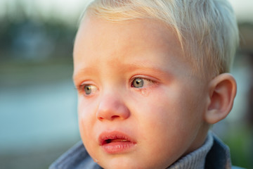 Little boy with tears close up defocused background. Emotional sad baby. Toddler sad face crying. Sad emotions. Hard to be toddler. Cute son crying face. Reasons baby crying. Tears on eyes