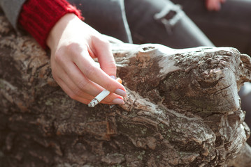 stressful young woman hand with cigarette by the tree