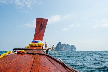 Front of the long tail boat on open sea with rocks. Traditional long tail boat at clear green water...