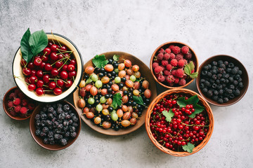 Ripe and sweet berries in bowls on  table. Gooseberry, blackberry, cherry, red and black currant
