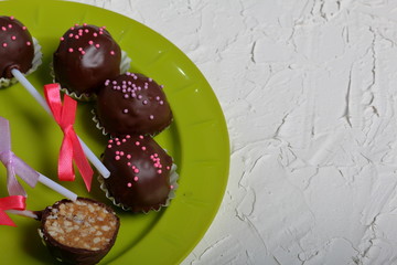 Homemade sweets. Chocolate coated sweets with almond filling. Cake pops decorated with a bow of braid. 