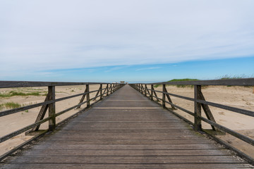 Fototapeta na wymiar Langer Holzsteg mit Sanddünen zum Meer