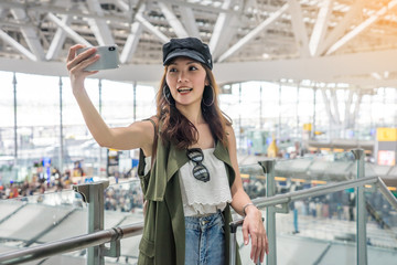 Backpacker travelers Asian women wearing hats are selfie with mobile phones During connecting the plane at the airport.Vacation and travel concept