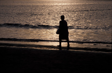 Señora caminado por la playa al anochecer