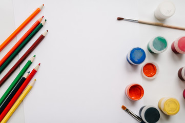 Place for text, design. The workspace of artist for drawing. Colored pencils, watercolor, paints, brush, sketchbook, white paper isolated on background table. Education concept.