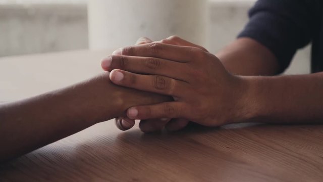 Close-up shot of couple holding hands in comfort