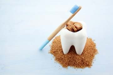 Ceramic tooth in big pile of brown sugar. Caries and sugar concept. Dental care concept