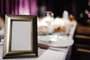 Mock up. Menu frame on table in restaurant. Blank blackboard. Stand for booklets with white sheets of paper, tent, card on cafeteria, blurred. Close up. Place for text.