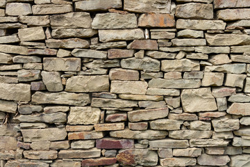 Fragment of a wall from a natural mountain stone with a small impregnation of dry branches