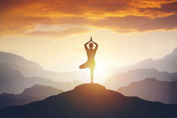 Man meditating on high mountain in sunset background