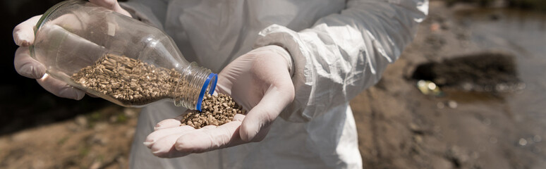 panoramic shot of ecologist in latex gloves holding bottle with pebbles