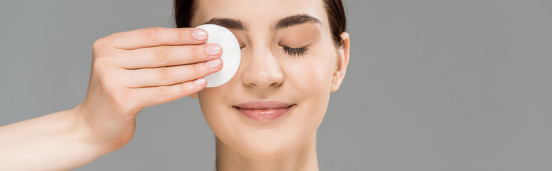 panoramic shot of cheerful naked woman covering eye with cotton pad isolated on grey