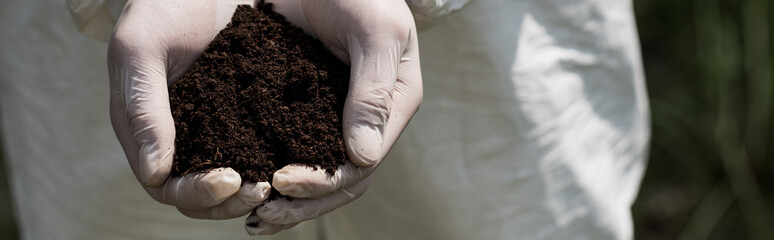 panoramic shot of ecologist in latex gloves holding handful of soil © LIGHTFIELD STUDIOS