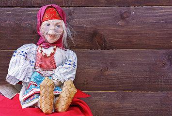 Vintage doll - a gray-haired grandmother in a national Russian dress and bast shoes on a brown...