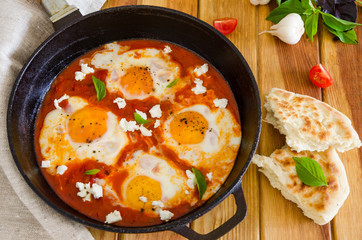 Shakshouka, dish of eggs poached in a sauce of tomatoes, chili, onions in the pan.