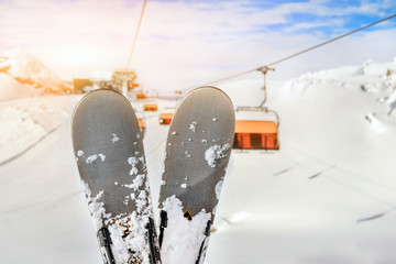 Close-up pair of skis on mountain winter resort with ski-lift and beautiful winter mountain panoramic scenic view