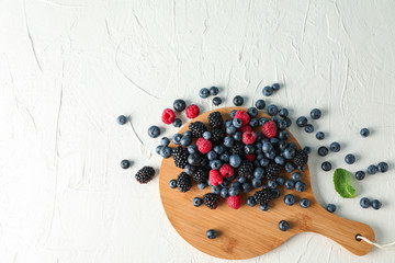 Flat lay composition with berries and cutting board on white cement background
