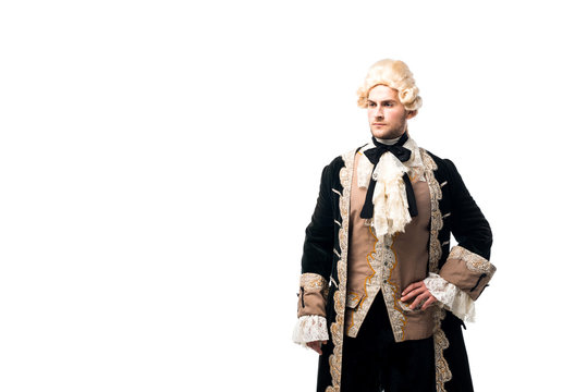 handsome victorian man in wig standing with hand on hip isolated on white