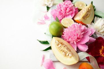 Still life with fresh assorted exotic fruits and peony flowers on white background. Concept of healthy eating with fruits and seasonal flowers. Wedding decor