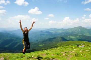 A happy 59 year old woman jumps on top of the highest mountain in the Carpathians. Ukrainian...