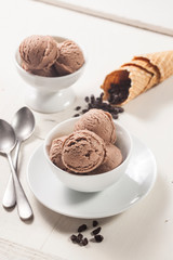 Chocolate ice cream bowls and chocolate chips are on the wooden surface. - 276556108