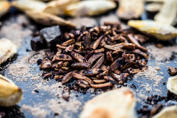 Popular Indian and Asian mukhwas or mouth freshener i.e. Aam Ki Ghuthli Ka Mukhwas consisting of ghee and hard-boiled mango seeds in a bowl on a wooden surface.Along with some raw dried mango seeds.