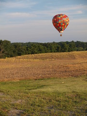 Hot air balloon hovers over farm fields
