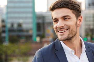 Cheery unshaved businessman outdoors on the street looking aside.