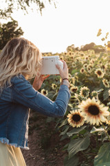 A young woman exploring a sunflower field at sunset