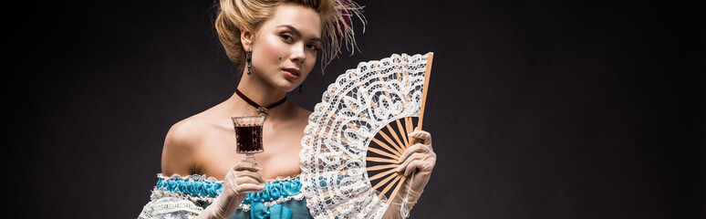 panoramic shot of victorian woman holding fan and wine glass on black
