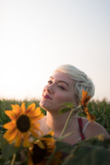 A women in her twenties with blonde hair exploring a sunflower field at sunset